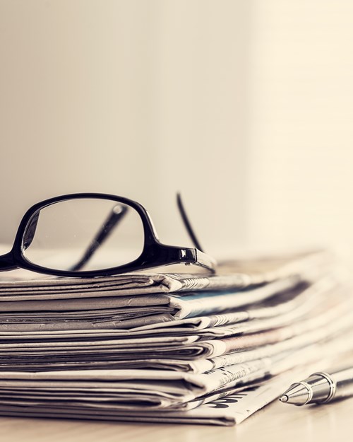 glasses on top of stacked newsletters