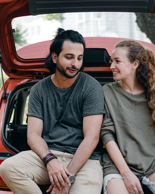 couple relaxing after unpacking their car for new home 